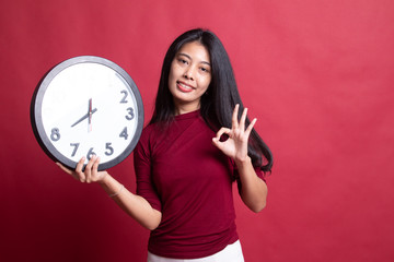 Young Asian woman show OK with a clock.
