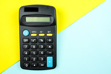 A calculator on yellow and blue  background.