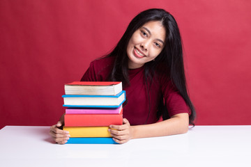 Happy young Asian woman read a book with books on table.
