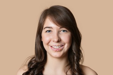 Portrait of a happy young woman with sprinkled lips over colored background