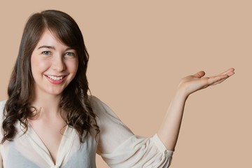 Portrait of a happy young woman with empty hand over colored background