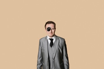 Portrait of a young businessman with eye patch over colored background