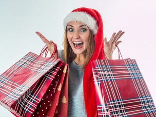 Young pretty woman in santa hat holding christmas bags