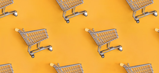 Pattern with shopping trolleys flat lay on yellow background. © Diana Vyshniakova