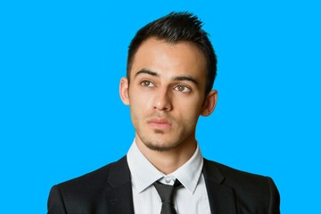 Thoughtful young businessman looking away over colored background