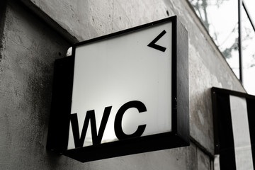 the WC or Water Closet sign attached on concrete wall with monochrome style