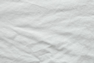 Close up shot of wrinkled white cotton shirt texture. Can see detail of the natural soft fabric. Crease Clothing textile or untidy bed sheet cover. Background wallpaper with copy space for edit