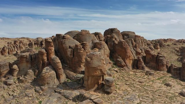Aerial around view on rock formations and stacked stones on granite hilltops, Baga Gazriin Chuluu, Gobi desert, Mongolia, 4k