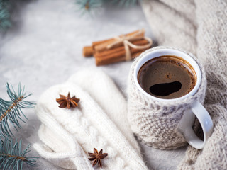 Knitted espresso coffee mug winter hot drink on table with homemade knitted wool white mittens and scarf