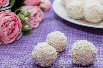 Homemade coconut candy on a background of pink flowers. Sweets for Valentine's Day.
