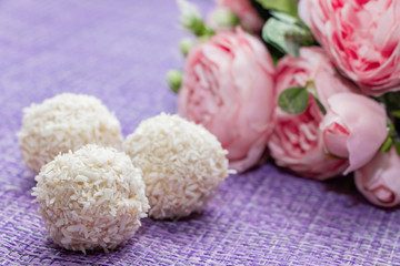 Homemade coconut candy on a background of pink flowers. Sweets for Valentine's Day.