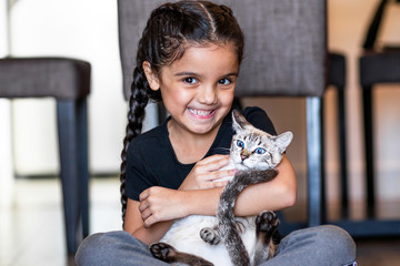 Sweet and Happy little girl child with her kitten cat on the floor in the house.  Brunette and brazilian. © CEXM