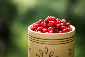 fresh ripe wild strawberries in a wooden bowl