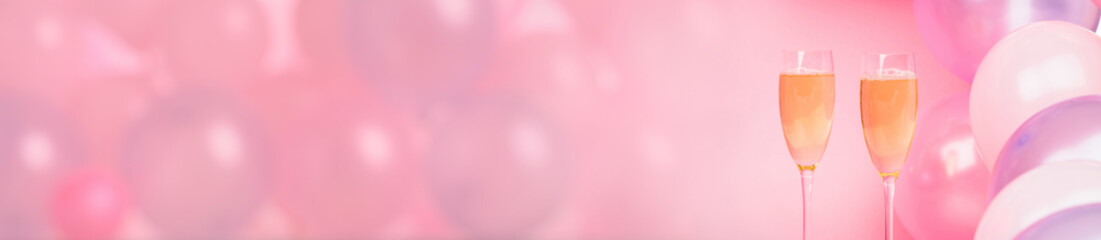 Two glasses of champagne on a pink background with pink balloons.
