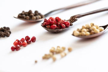 bunte pfefferkörner auf weißem grund zum würzen in der küche