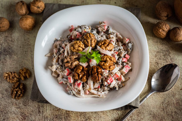 Delicious salad with squid and walnuts. Seafood salad in a white plate on a gray background