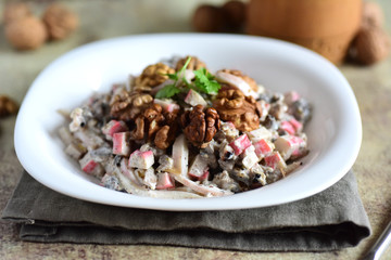 Delicious salad with squid and walnuts. Seafood salad in a white plate on a gray background