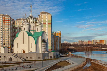 An unusual Orthodox church under construction stands on the river bank against the background of...