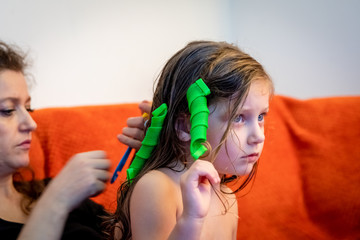 mother is putting hair curlers in hers daughter's hair