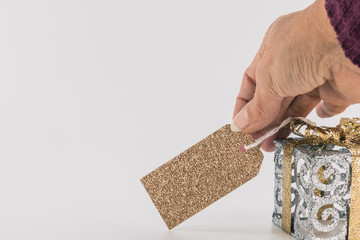 Main de femme tenant une étiquette dorée à paillettes avec un espace texte accrochée à un...