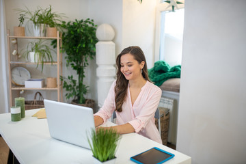 Positive young woman working on her laptop
