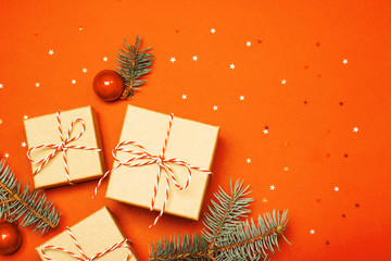 Christmas composition with gifts, branches and holiday elements on the orange background. Flat lay....