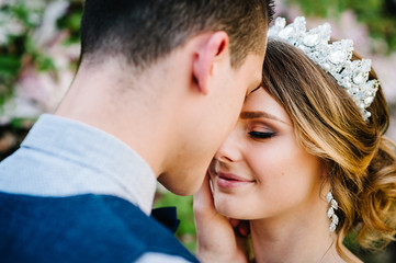 Fototapeta premium Stylish happy bride, woman with crown and groom, man. Newlyweds are hugging. Close up. On the background of nature. Weddings, engagement, marriage proposal, dating.