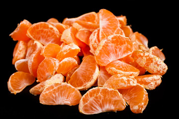 Heap of tangerine pieces isolated on a black background.