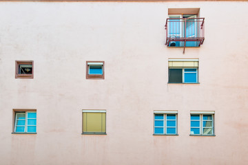 The outside of a typical European building. The front is bright, with several characteristic windows and balconies.