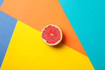 Half of juicy grapefruit on multicolored background, space for text