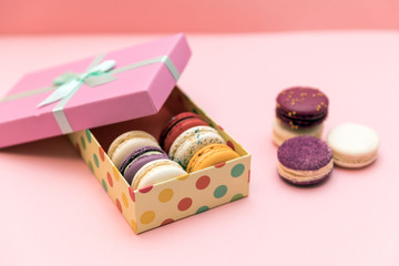 Multi-colored macaroon cakes on a blue pastel background in the gift box