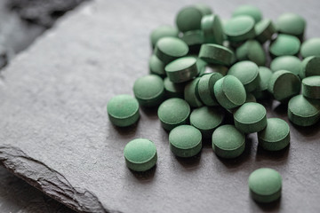 grüne Spirulina als Nahrungsergänzungsmittel auf grauem Grund