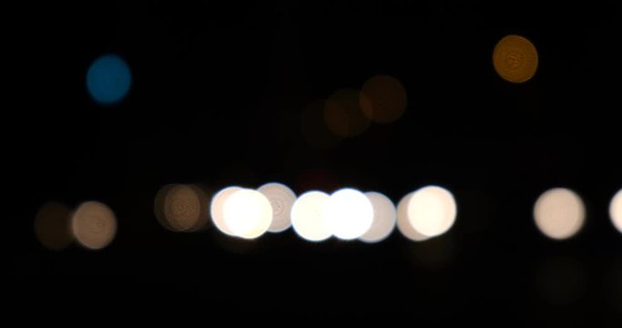 Extreme out of focus car healdlights at night moving from left to right in a busy intersection in Paris, France.