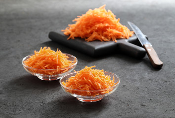 Still life with carrots on a dark background, vegetable salad with carrots, grated carrots