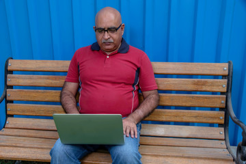 Indian man using a laptop outdoors at Pune India.