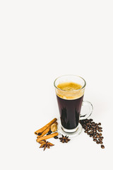 GLASS CUP OF COFFEE WITH CINNAMON ON WHITE BACKGROUND