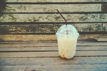 Iced coffee on a wooden table, Iced coffee on a blurred wooden table, wooden wall in the background