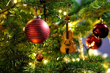 Violin in christmas tree decoration with red baubles
