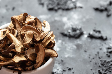 braune geschnittene gesammelte getrocknete Pilze auf grauem Grund im Herbst in einer weißen schale