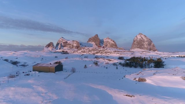 Winter in Tr&aelig;na, iconic mountains of Sanna island, revealing salmon farm, Nordland, Northern Norway, aerial drone shot