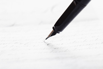 Fototapeta premium Fountain pen on an ancient handwritten letter. Old story. Retro style.