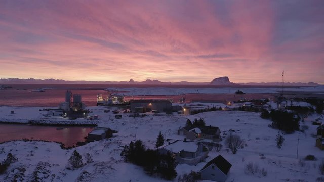 Winter sunrise over Hus&oslash;ya village and port, Tr&aelig;na islands, Nordland, Northern Norway, aerial drone shot