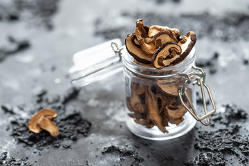 braune geschnittene gesammelte getrocknete Pilze auf grauem Grund im Herbst in einem Einmachglas