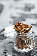 braune geschnittene gesammelte getrocknete Pilze auf grauem Grund im Herbst in einem Einmachglas