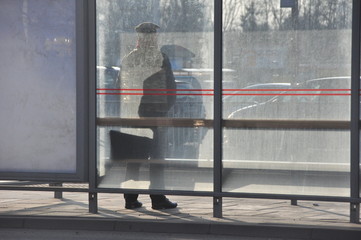 Silhouette waiting at glass bus stop in urban setting