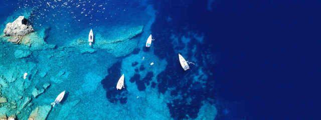 Fototapeta na wymiar Aerial drone photo of sail boats docked in turquoise exotic island bay with crystal clear sea