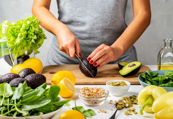 Woman cuts avocado in the kitchen. cooking healthy food concept.