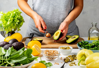 Woman preparing avocado for eating in the kitchen. cooking healthy food concept.