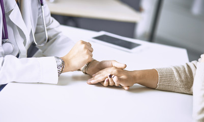 Woman doctor calms patient and holds hand