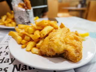 Wide closeup of a large plate of fish and chips made from locally caught cod fish. Weymouth, Dorset, United Kingdom. Travel and cuisine.